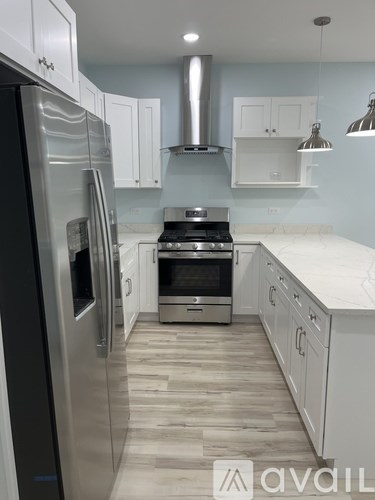 A kitchen with a black refrigerator and white cabinets.