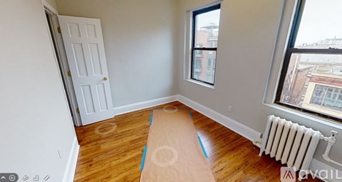A room with a white door, a window, and a radiator on the wall.