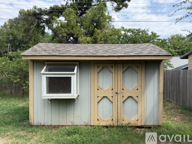 A shed with a grey and white exterior and a brown roof.