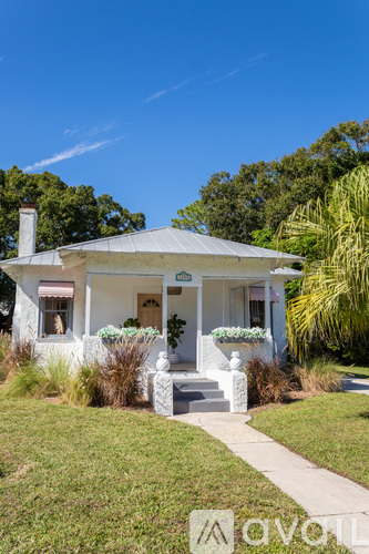 A white house with a porch and a white statue in front.