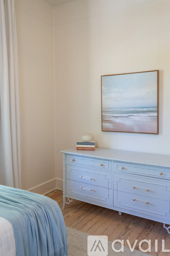 A bedroom with a white dresser and a painting on the wall.