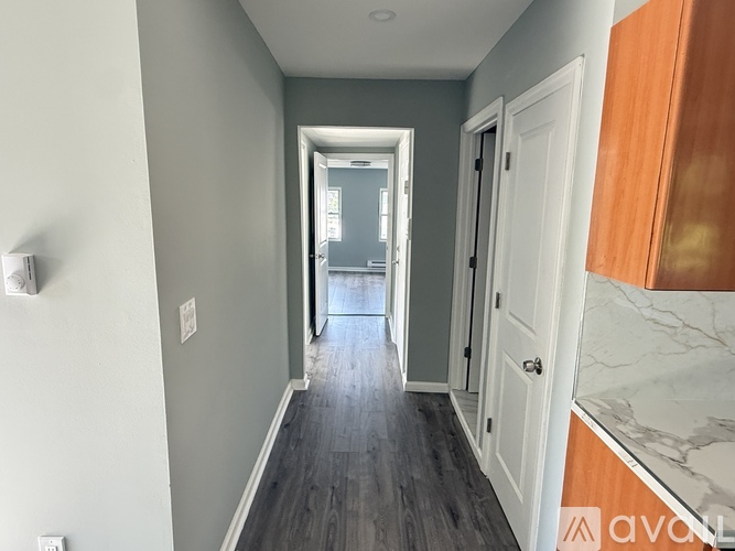 A hallway with a wooden floor and white walls.
