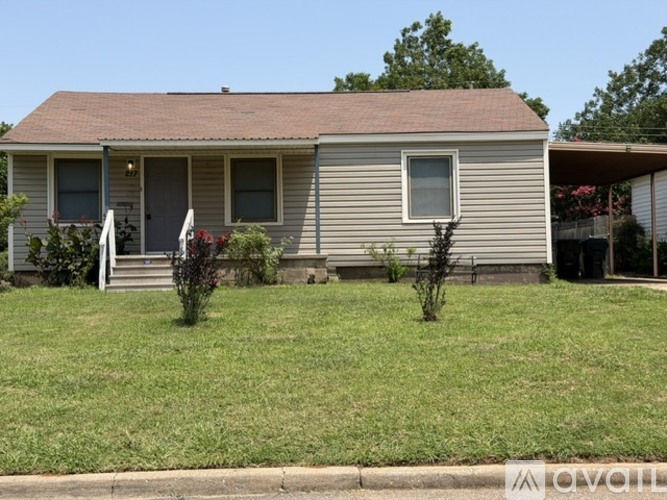 A house with a brown roof and grey siding with a small front yard.