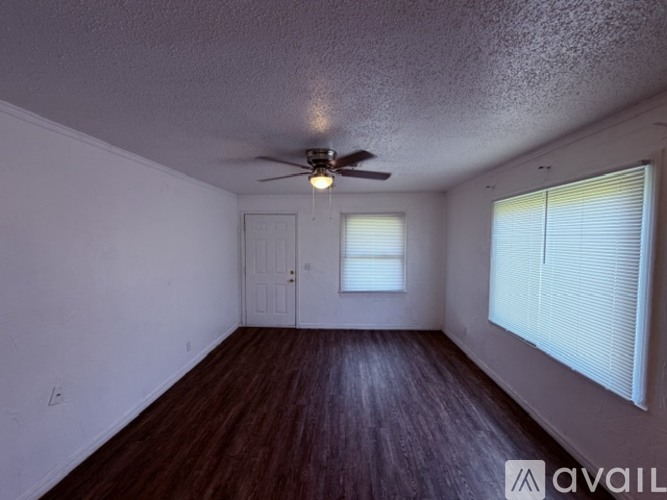 A room with a ceiling fan and wooden flooring.