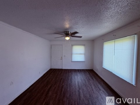A room with a ceiling fan and wooden flooring.