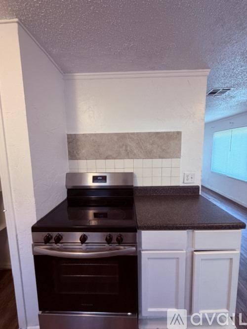 A kitchen with a stove top oven and a black counter top.