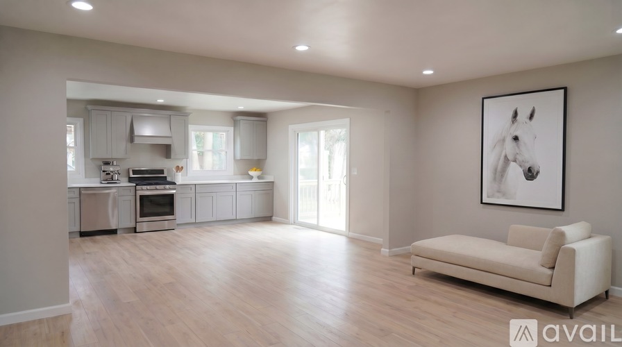 A spacious living room with a kitchen in the background and a couch in the foreground.