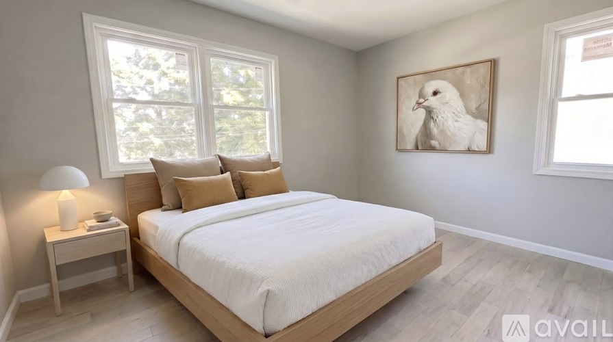 A bedroom with a large bed, a nightstand with a lamp, and a framed picture of a white dove on the wall.