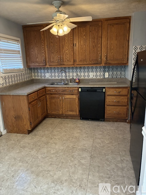 A kitchen with wooden cabinets and a black dishwasher.