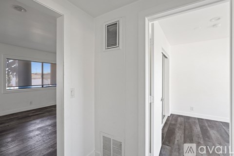 A room with white walls and a window with a view of a building outside.