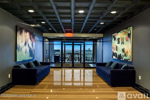 A modern living room with a dark blue sofa and a large painting on the wall.