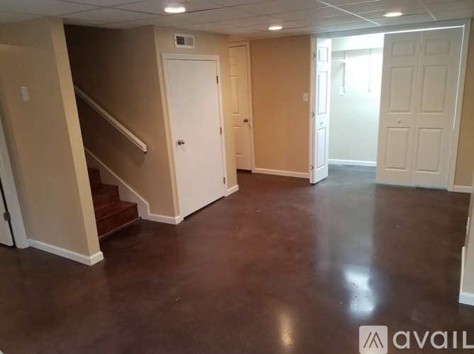 A spacious room with brown flooring and white doors.