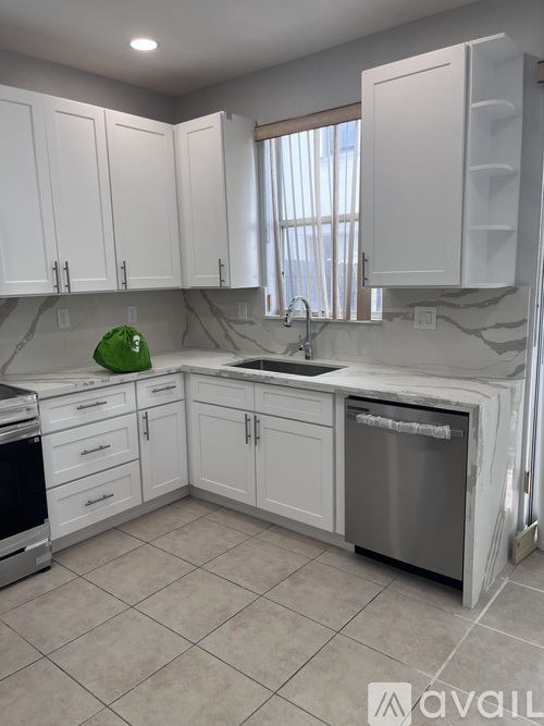 A kitchen with white cabinets and a marble countertop.