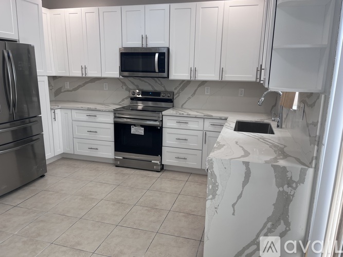 A kitchen with white cabinets and a marble countertop.