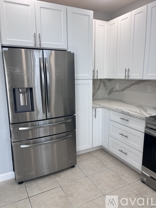 A stainless steel refrigerator in a kitchen with white cabinets.