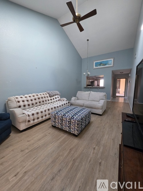 A living room with a white couch and a patterned ottoman.
