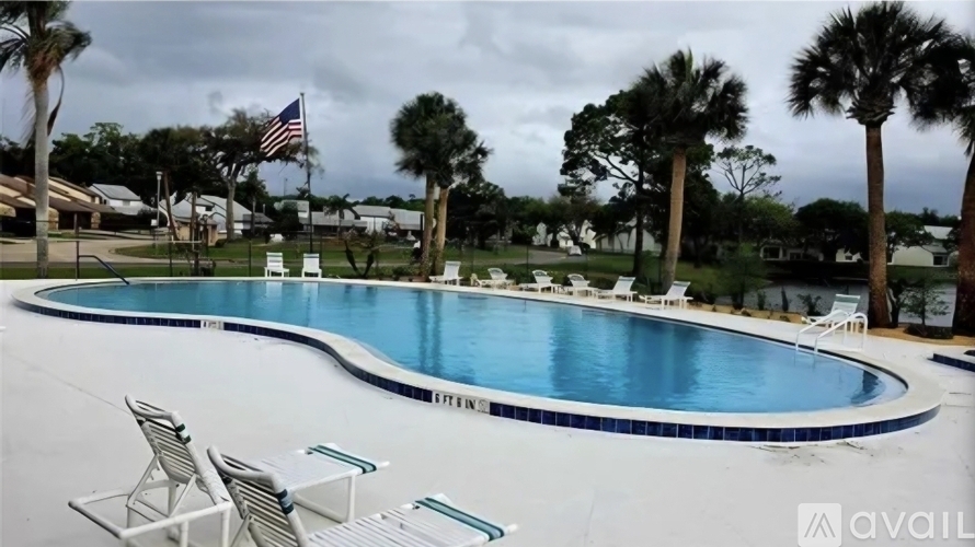 A pool with chairs and an American flag in the background.