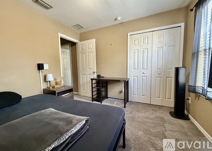 A bedroom with a bed, dresser, and a nightstand with a lamp.