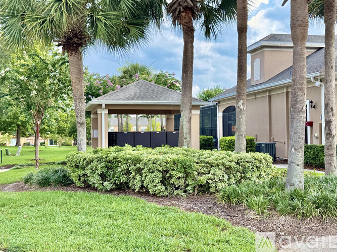 A gazebo is surrounded by palm trees and bushes.