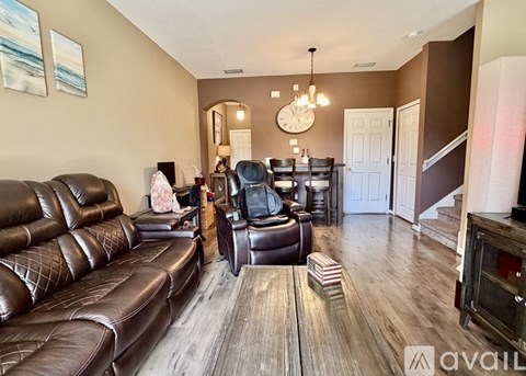 A living room with brown leather furniture and a wooden floor.