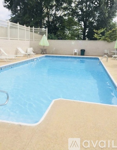 A swimming pool with a white fence and green trees in the background.