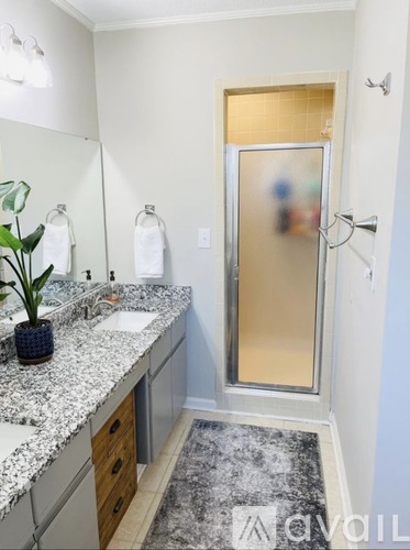 A bathroom with a frosted glass shower door and a marble countertop.