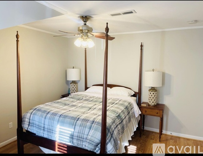 A bedroom with a four poster bed and a ceiling fan.