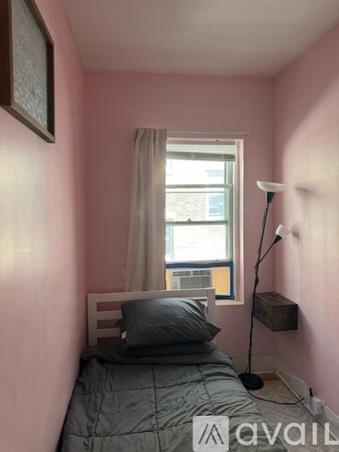A bedroom with pink walls and a window with curtains.