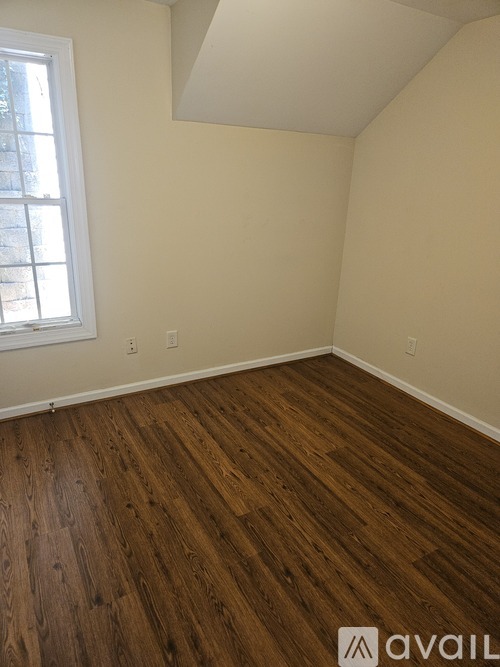 A room with wooden flooring and a window.