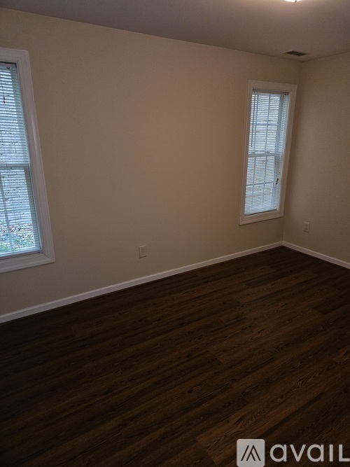 A room with wooden flooring and a window with blinds.