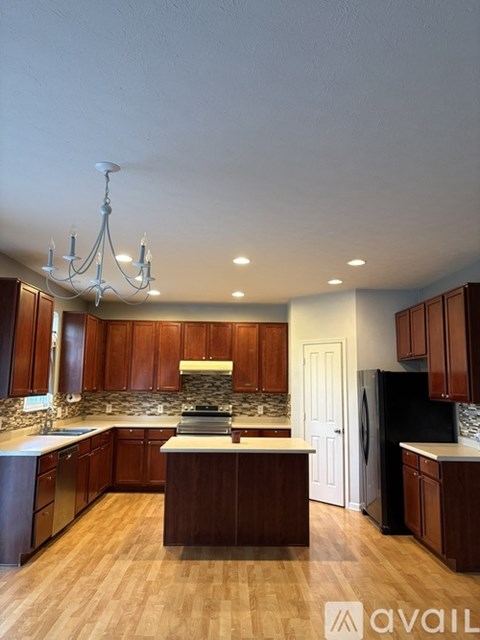 A kitchen with wooden cabinets and a black refrigerator.