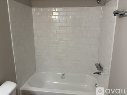 A white bathtub in a bathroom with white tiles.