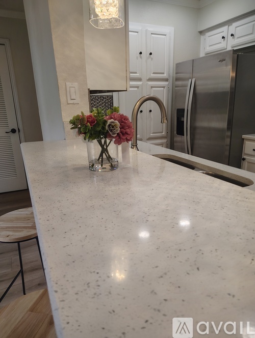A kitchen with a marble countertop and a vase of flowers.