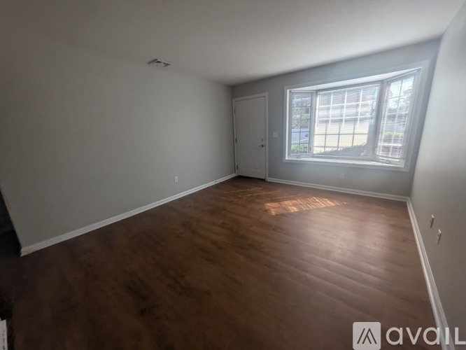 A room with wooden flooring and a window letting in natural light.