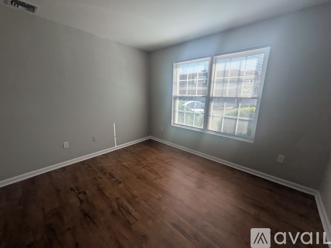 A room with wooden flooring and a window showing an outdoor view.