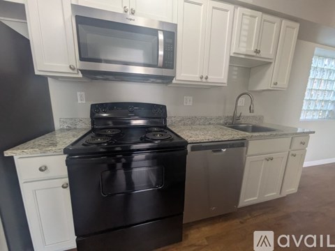 A kitchen with a black stove top oven and white cabinets.