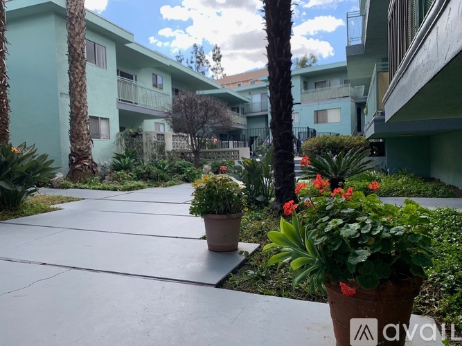 A concrete walkway leads through a courtyard with potted plants and trees.