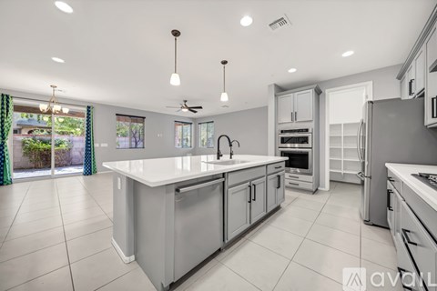 A spacious kitchen with a central island, double ovens, and a refrigerator with a freezer on the side.