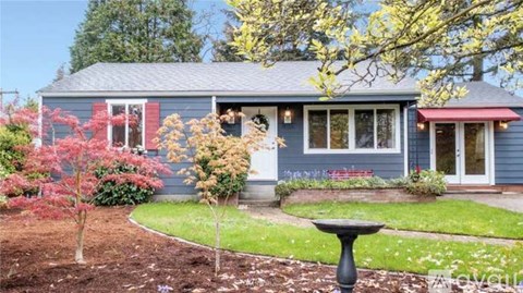 A blue house with a red awning and a small garden in front.