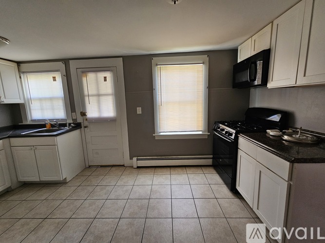 A kitchen with white cabinets and a black stove top oven.