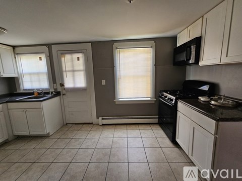 A kitchen with white cabinets and a black stove top oven.