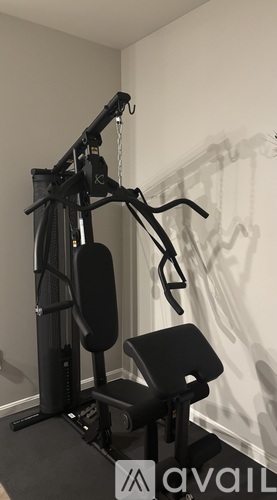 A black home gym machine with a black seat and a black handlebar.
