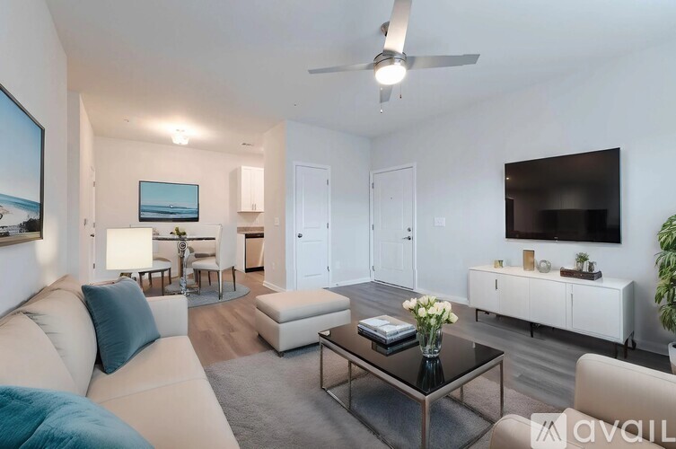 A living room with a white couch, a coffee table, and a television.