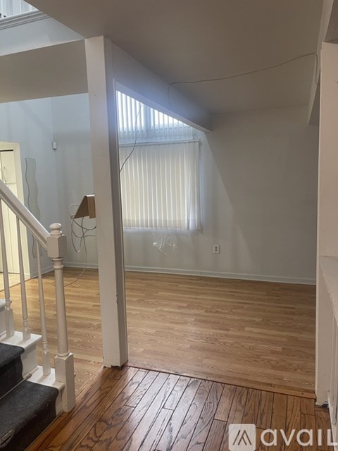 A room with wooden floors and a staircase leading to another room.