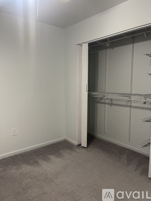 A room with a white wall and a white closet with shelves.