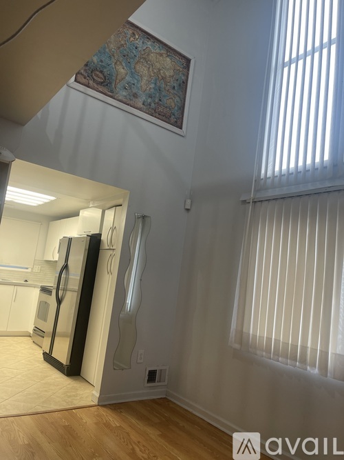 A kitchen with a fridge and a window with blinds.