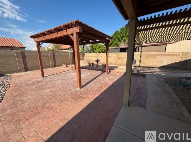 A patio with a wooden pergola and a brick walkway.