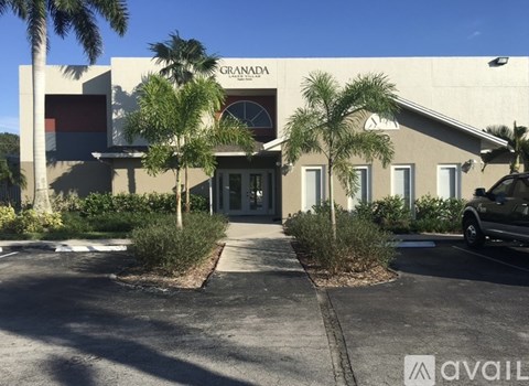 The image shows a building with the name "GRANADA" on it, surrounded by palm trees and a clear sky.