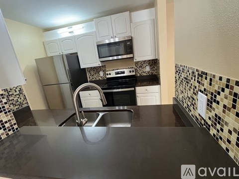 A kitchen with a black counter top and white cabinets.
