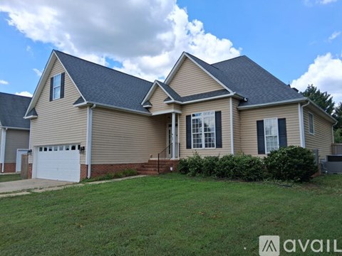 A house with a beige exterior and a black roof is for sale.